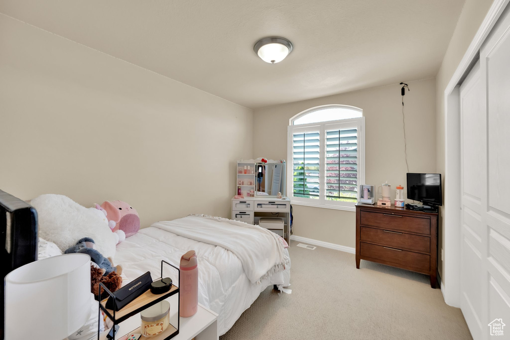 Bedroom with light colored carpet, baseboards, and a closet