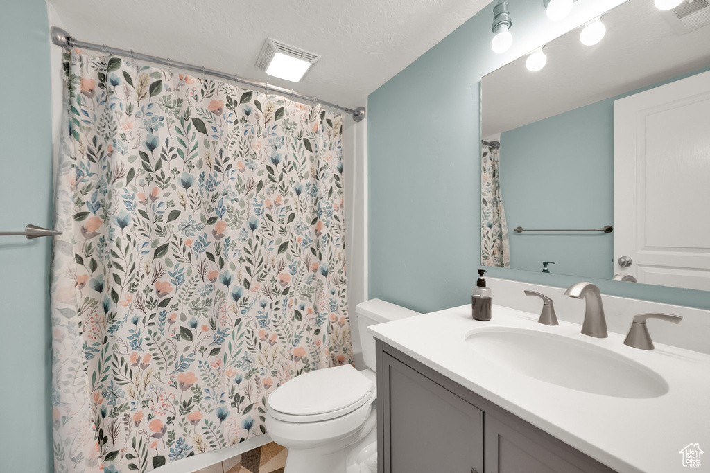 Full bath with toilet, visible vents, curtained shower, and vanity