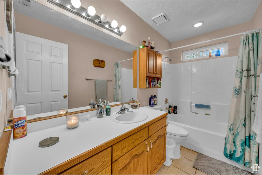 Bathroom featuring tile patterned flooring, toilet, shower / bathtub combination with curtain, and vanity