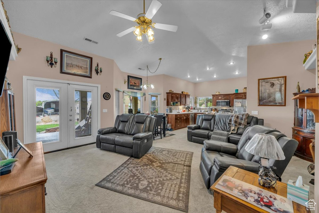 Living room with french doors, a ceiling fan, visible vents, light carpet, and lofted ceiling