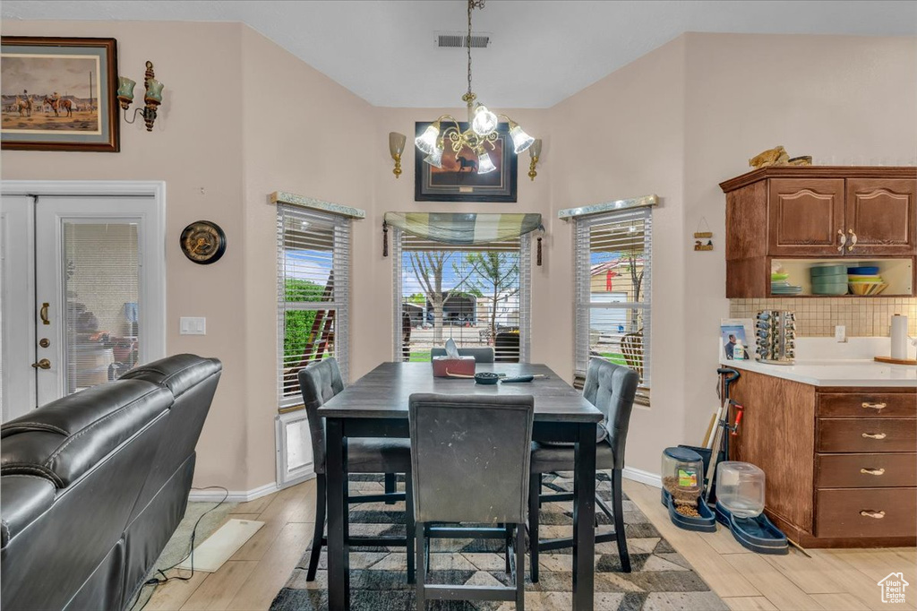 Dining space featuring baseboards, light wood finished floors, an inviting chandelier, and visible vents