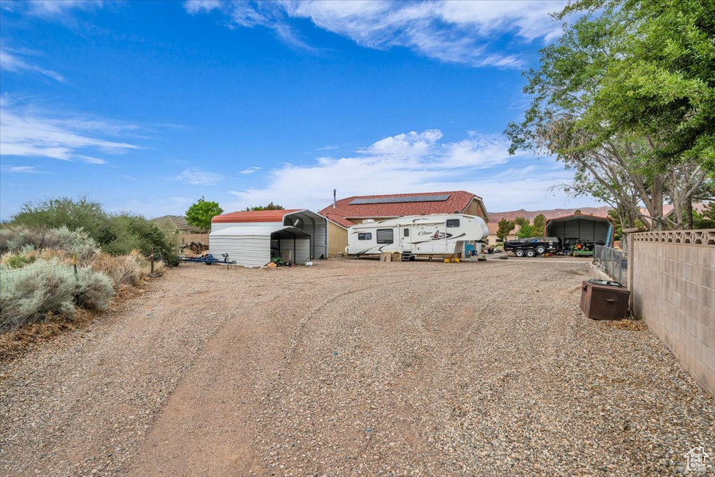 View of yard with fence, a storage shed, an outdoor structure, driveway, and a carport