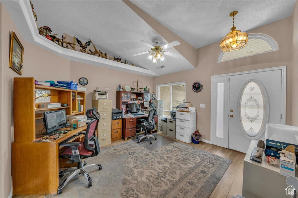 Office space featuring lofted ceiling, light wood-style floors, ceiling fan, and a textured ceiling