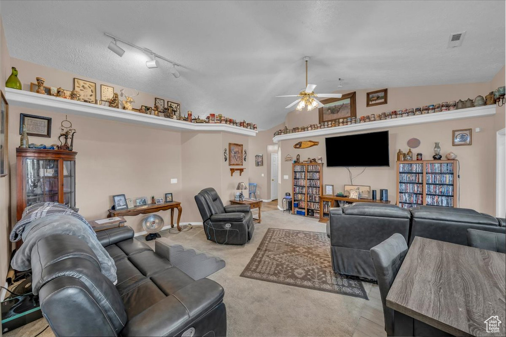 Carpeted living room featuring visible vents, ceiling fan, and vaulted ceiling