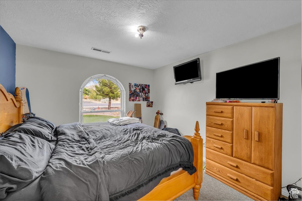 Bedroom with carpet flooring, a textured ceiling, and visible vents
