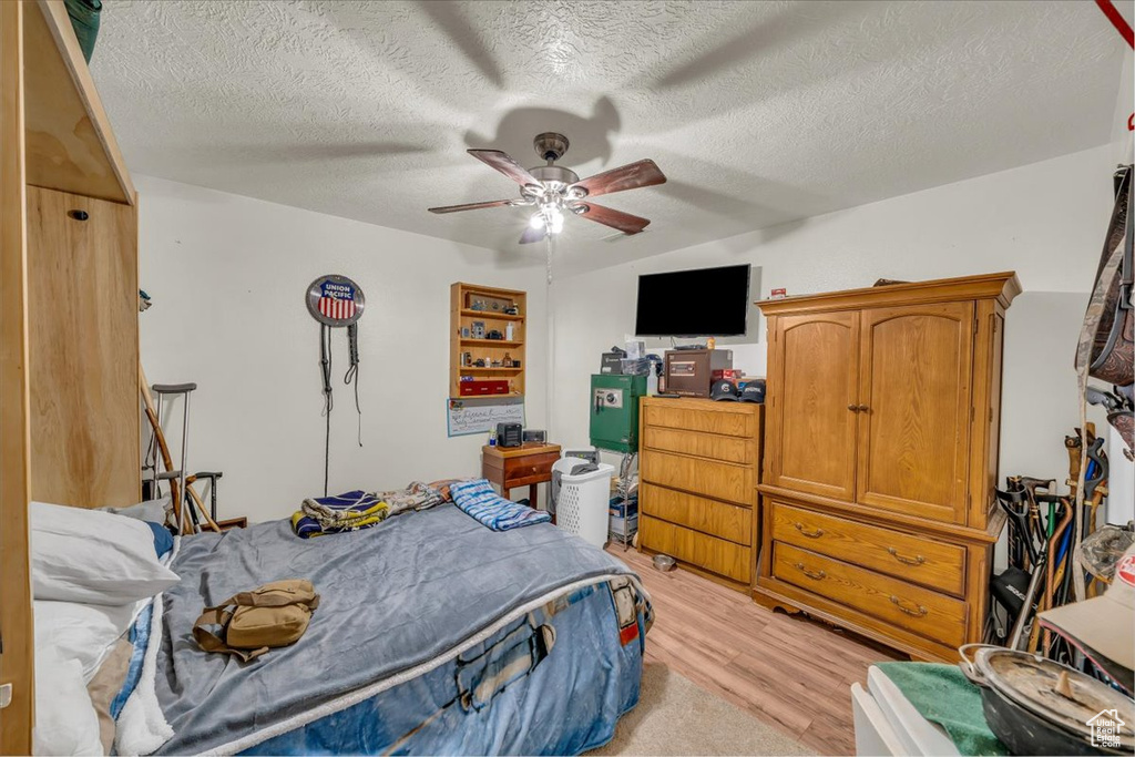Bedroom featuring light wood finished floors, a textured ceiling, and a ceiling fan