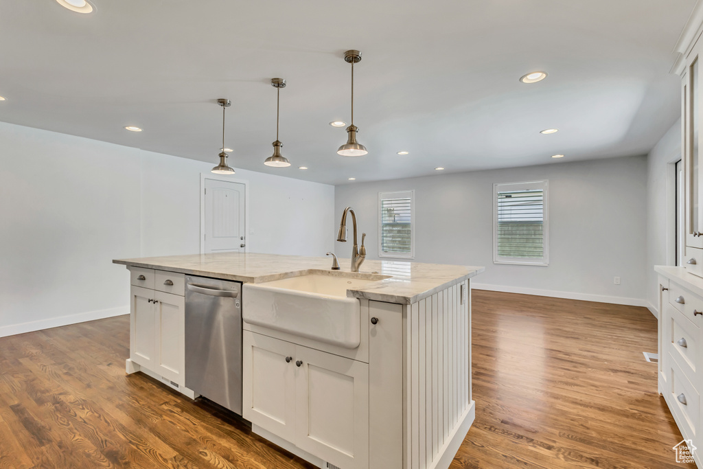 Kitchen with a sink, stainless steel dishwasher, decorative light fixtures, and wood finished floors