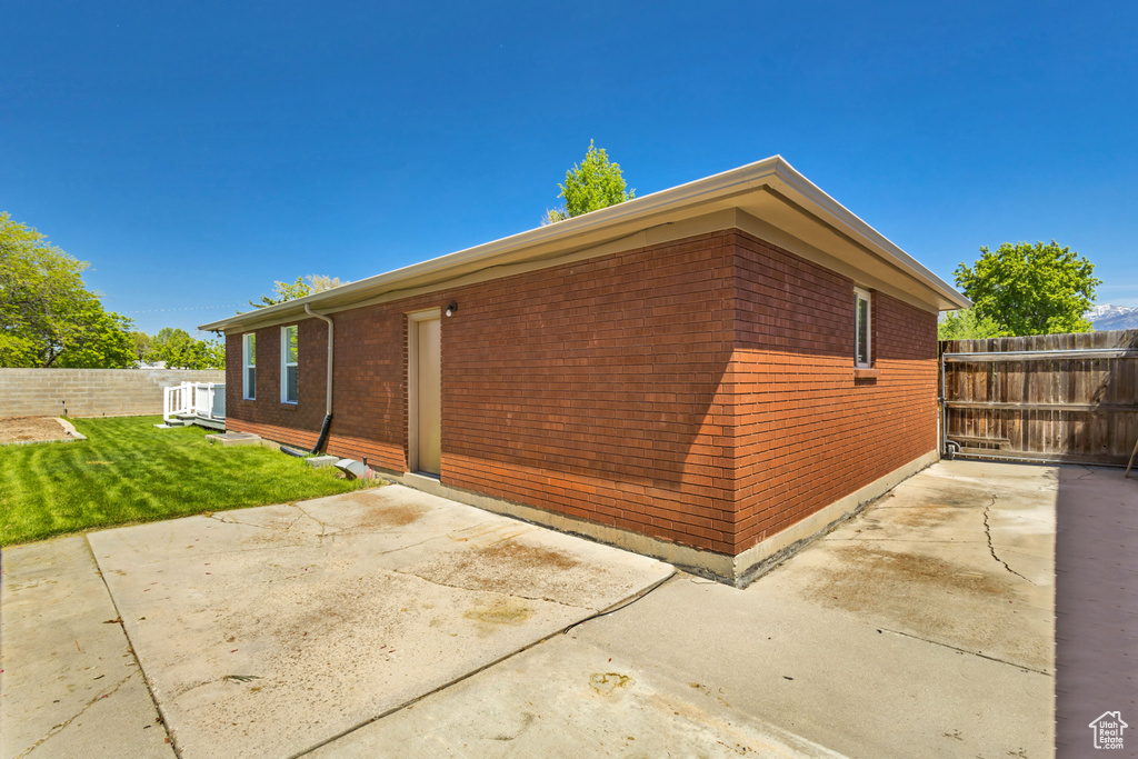 View of property exterior with fence, a patio, and brick siding