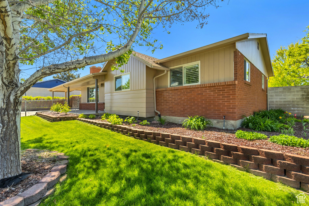 View of front of property featuring board and batten siding, brick siding, fence, a patio, and a front yard