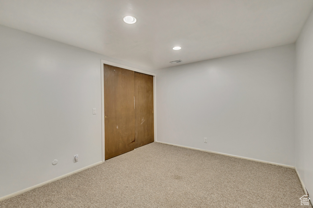 Unfurnished bedroom with a closet, carpet floors, visible vents, baseboards, and recessed lighting