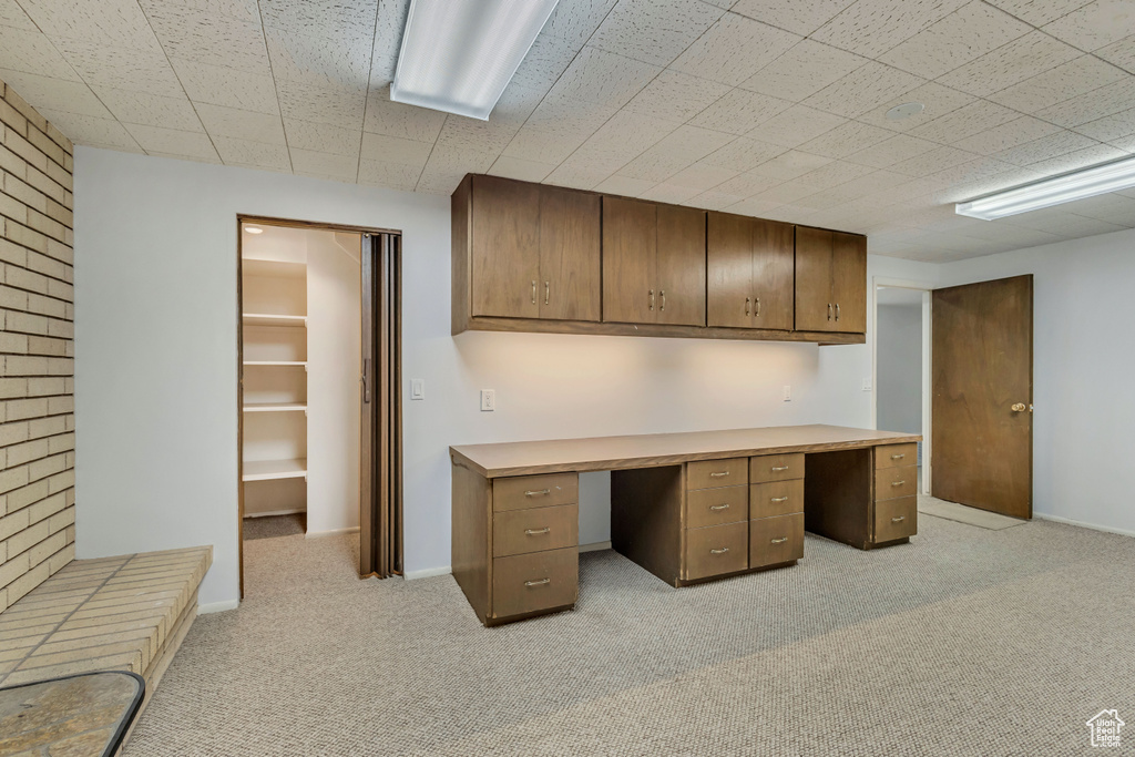 Unfurnished office featuring baseboards, light carpet, and built in study area
