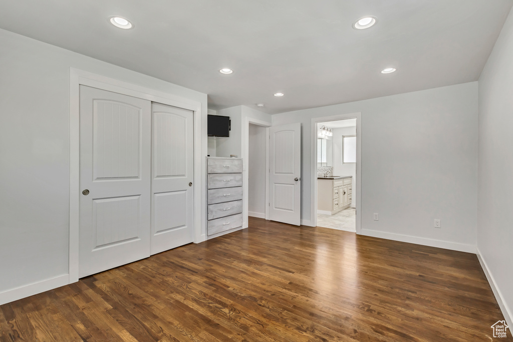 Unfurnished bedroom featuring a closet, dark wood-style flooring, baseboards, and recessed lighting