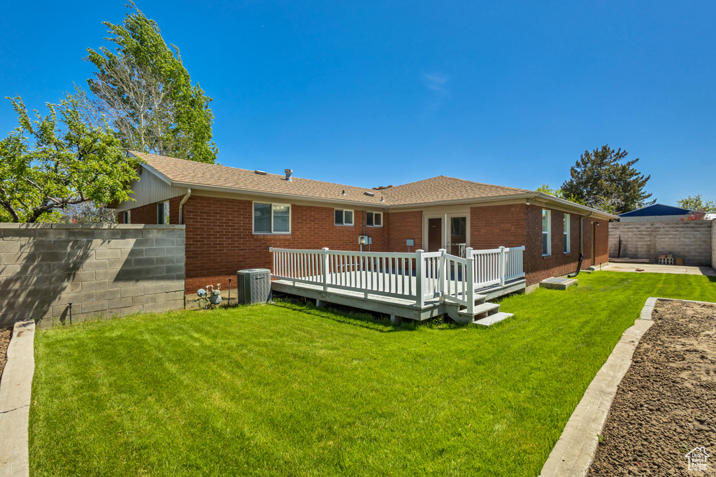 Rear view of property with brick siding, a lawn, a fenced backyard, and central AC