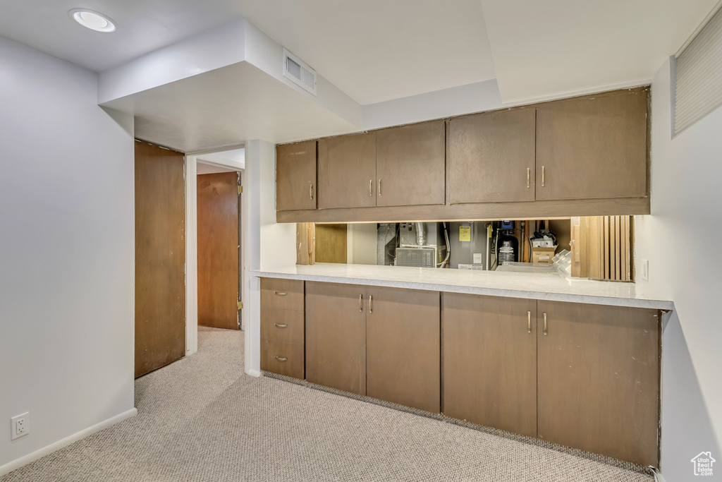Kitchen with light colored carpet, light countertops, visible vents, and baseboards