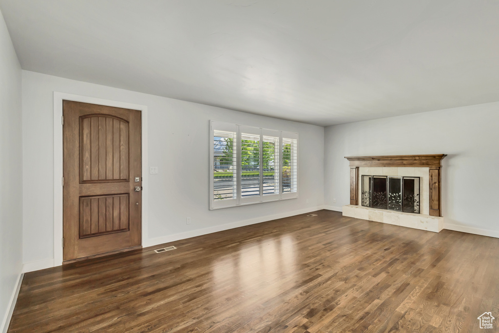 Unfurnished living room with a premium fireplace, baseboards, visible vents, and wood finished floors