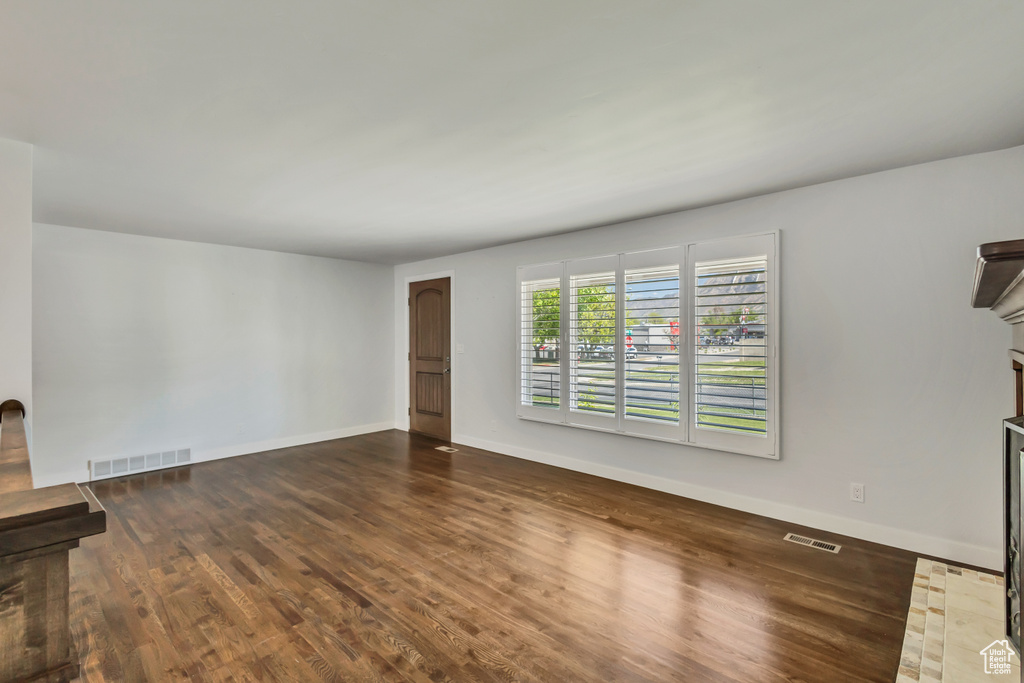 Unfurnished living room with baseboards, visible vents, and wood finished floors