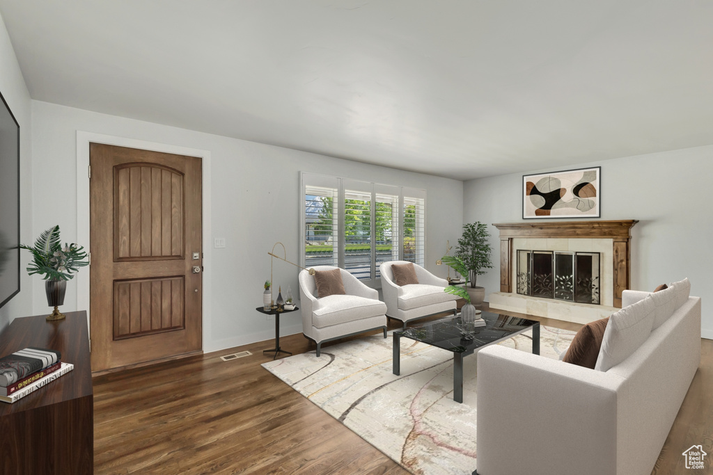 Living area with dark wood-type flooring, baseboards, visible vents, and a high end fireplace