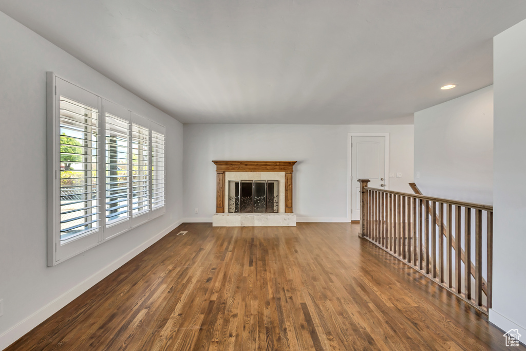 Unfurnished living room featuring a fireplace, baseboards, dark wood-type flooring, and recessed lighting