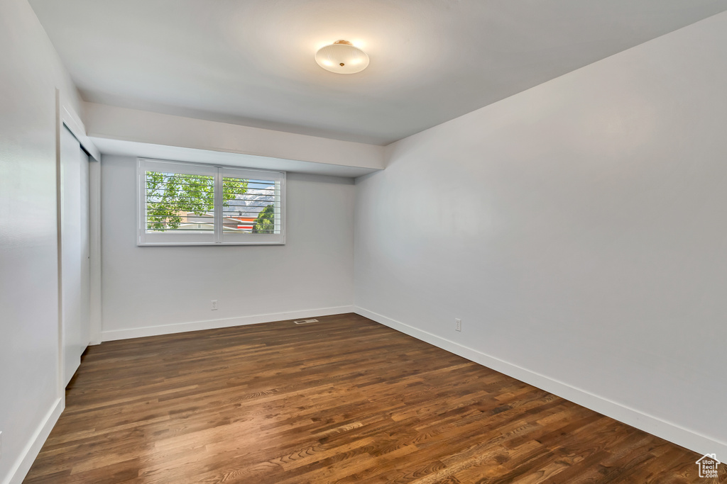 Unfurnished room featuring baseboards and dark wood-style flooring