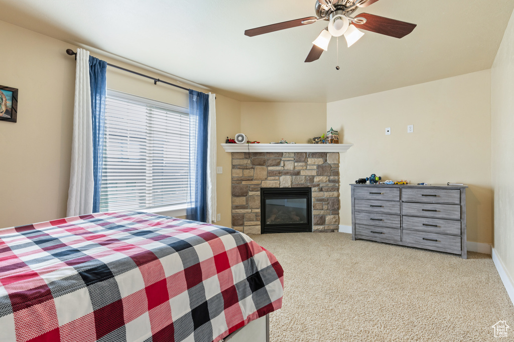 Carpeted bedroom featuring baseboards, a fireplace, and a ceiling fan