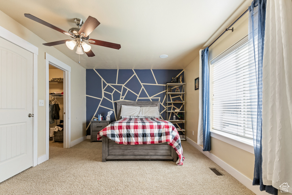 Carpeted bedroom featuring ceiling fan, a spacious closet, visible vents, and multiple windows