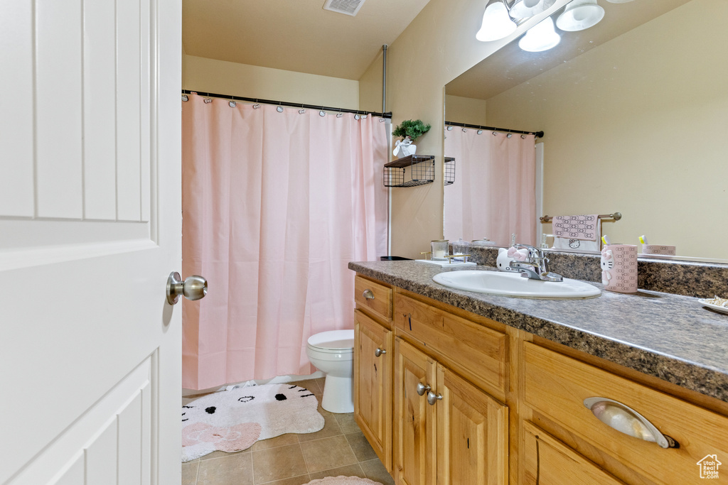 Bathroom featuring toilet, curtained shower, visible vents, tile patterned flooring, and vanity
