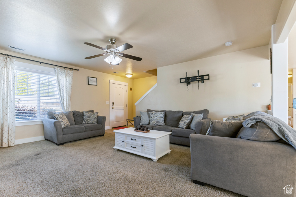 Carpeted living room featuring visible vents, baseboards, and ceiling fan