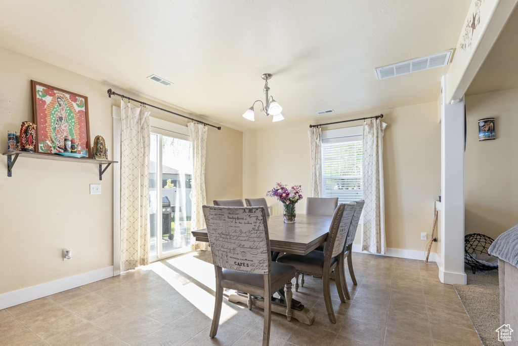 Dining area with a chandelier, a wealth of natural light, and visible vents