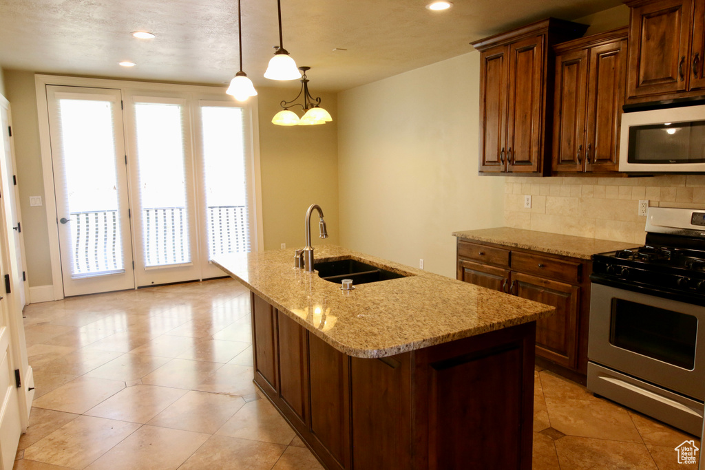 Kitchen with stainless steel gas stove, white microwave, a sink, and plenty of natural light