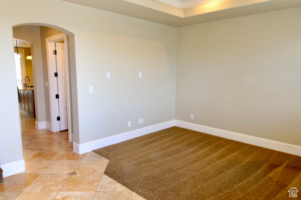 Empty room with light tile patterned floors, baseboards, and arched walkways