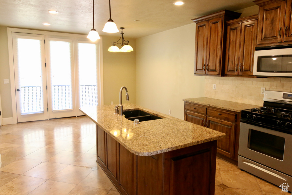 Kitchen with white microwave, stainless steel gas range oven, a wealth of natural light, and a sink