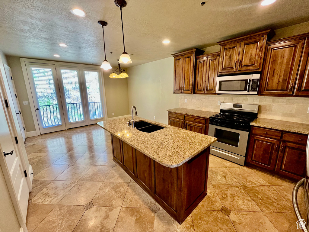 Kitchen featuring a sink, stainless steel gas stove, baseboards, and backsplash