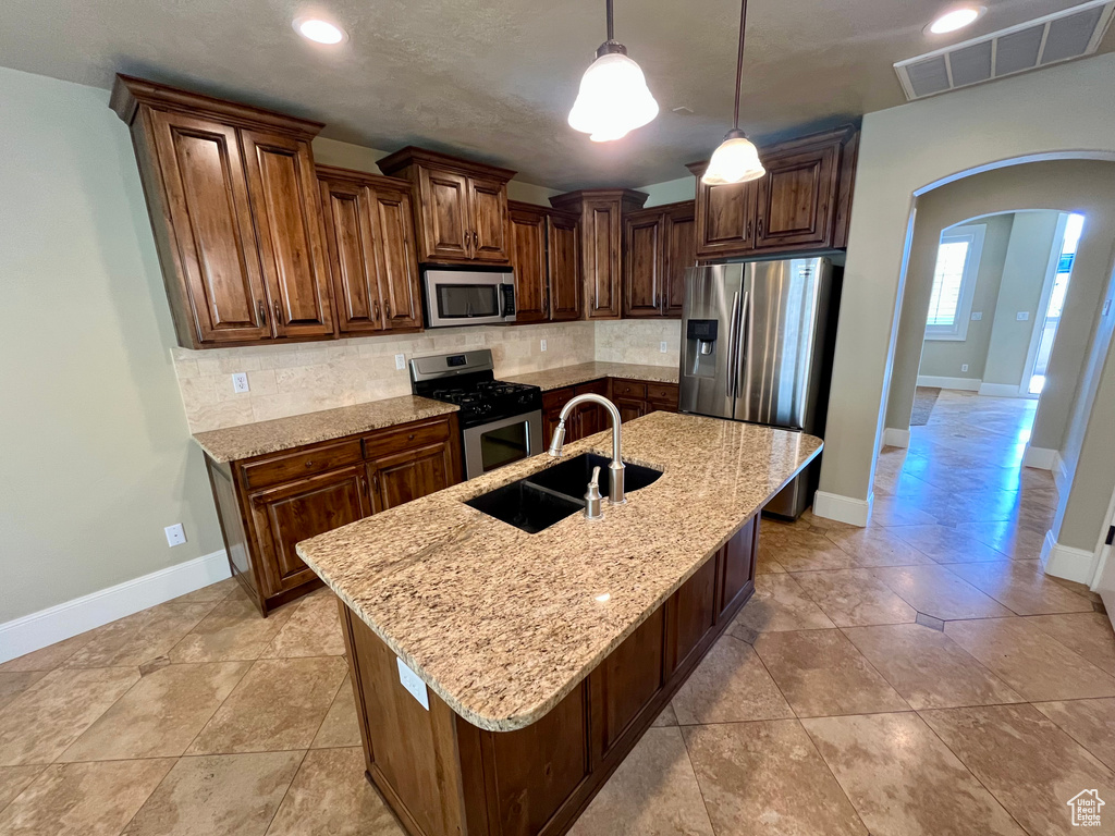Kitchen with visible vents, a sink, arched walkways, stainless steel appliances, and tasteful backsplash