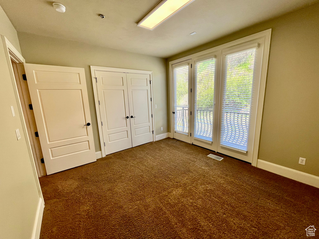 Unfurnished bedroom with a closet, visible vents, carpet floors, baseboards, and access to exterior