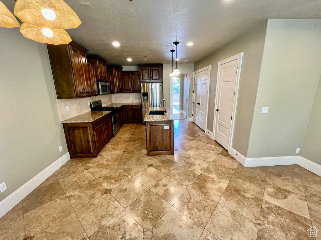 Kitchen featuring baseboards, light stone countertops, appliances with stainless steel finishes, tasteful backsplash, and recessed lighting