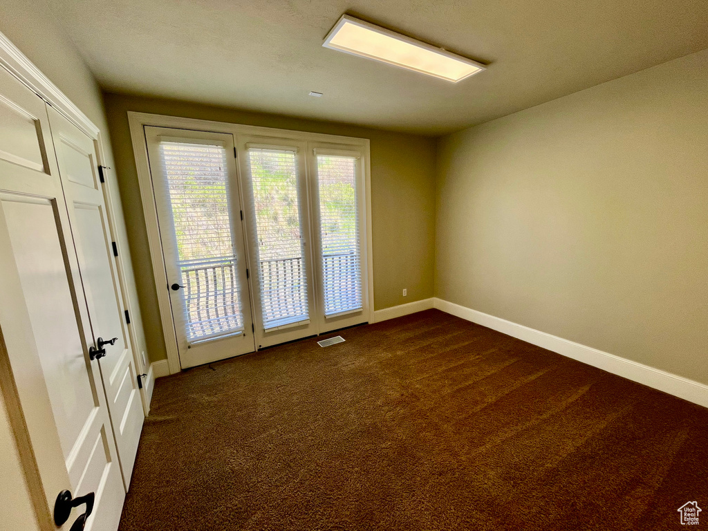 Spare room with baseboards, dark carpet, and visible vents