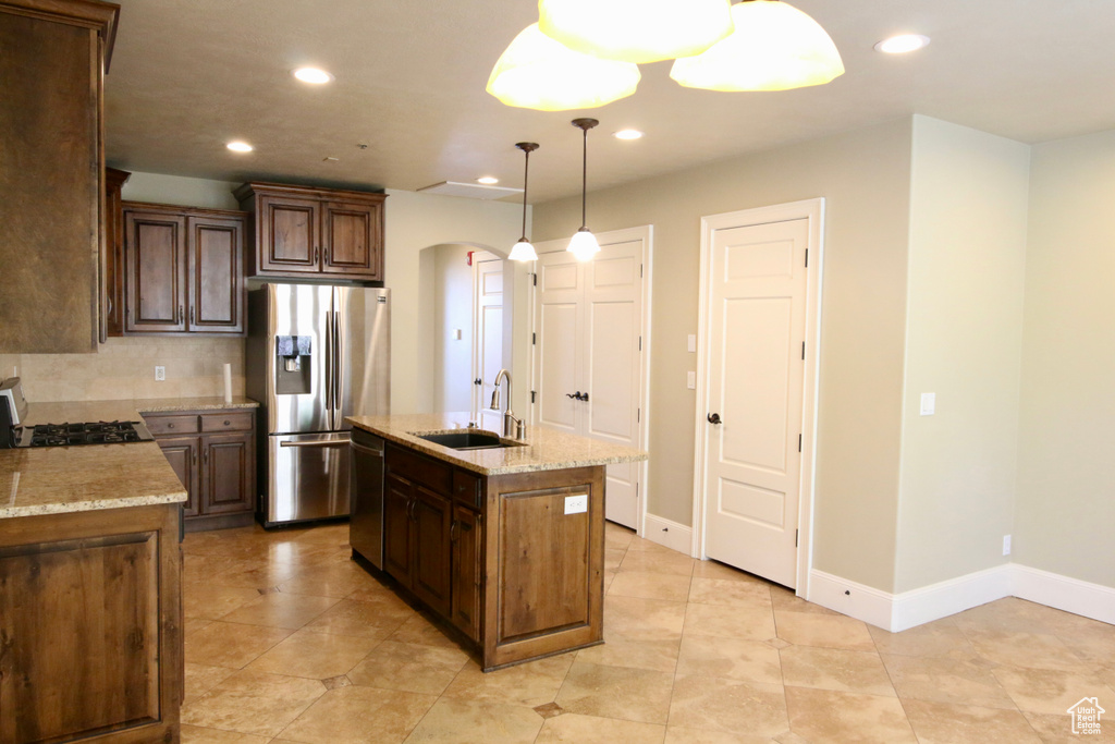 Kitchen with a sink, recessed lighting, arched walkways, and appliances with stainless steel finishes