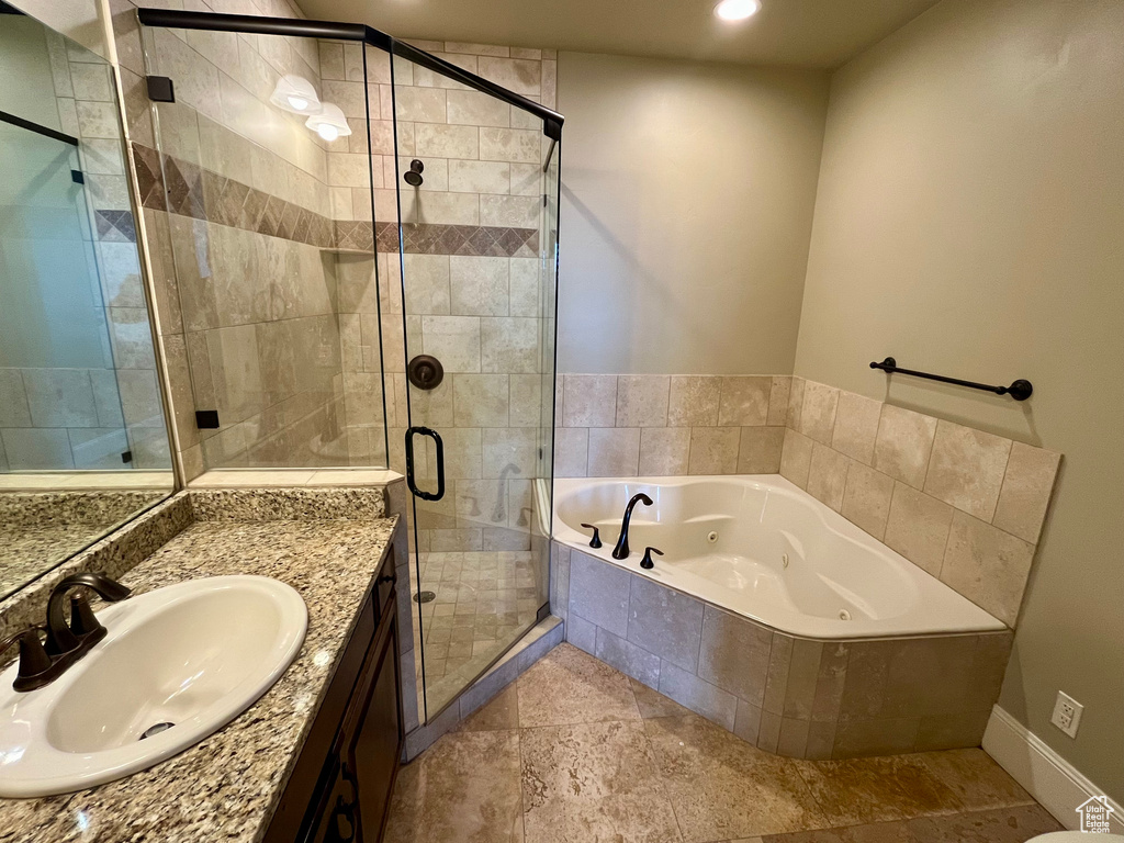 Bathroom featuring a tub with jets, vanity, recessed lighting, a stall shower, and baseboards