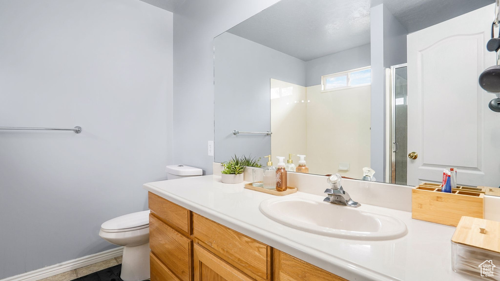 Bathroom featuring vanity, toilet, baseboards, and a shower stall