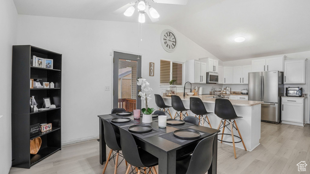 Dining space with ceiling fan, lofted ceiling, and light wood-type flooring