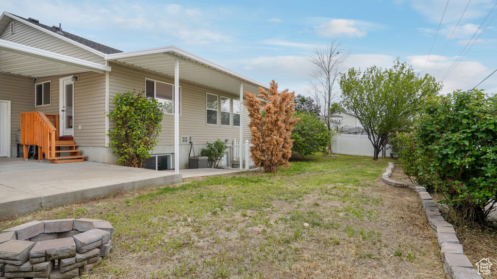 View of yard with an outdoor fire pit, central air condition unit, a patio, and fence