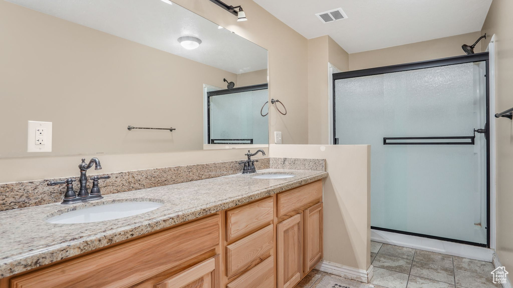 Bathroom with a sink, double vanity, a stall shower, and visible vents