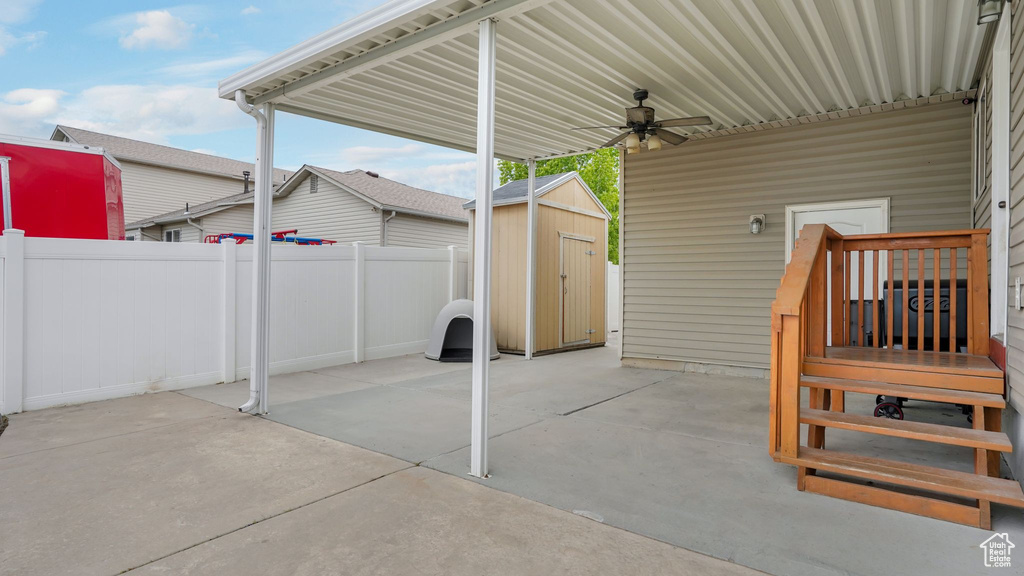 View of patio / terrace featuring an outdoor structure, fence, ceiling fan, and a storage unit