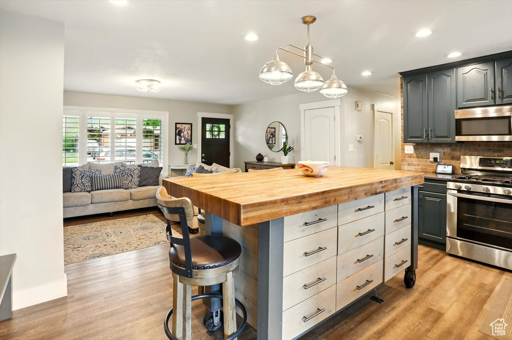 Kitchen featuring butcher block countertops, light wood-style floors, and appliances with stainless steel finishes