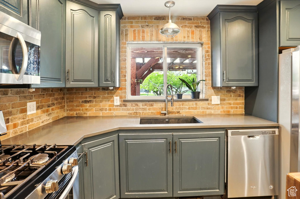 Kitchen with light countertops, decorative backsplash, stainless steel appliances, and a sink