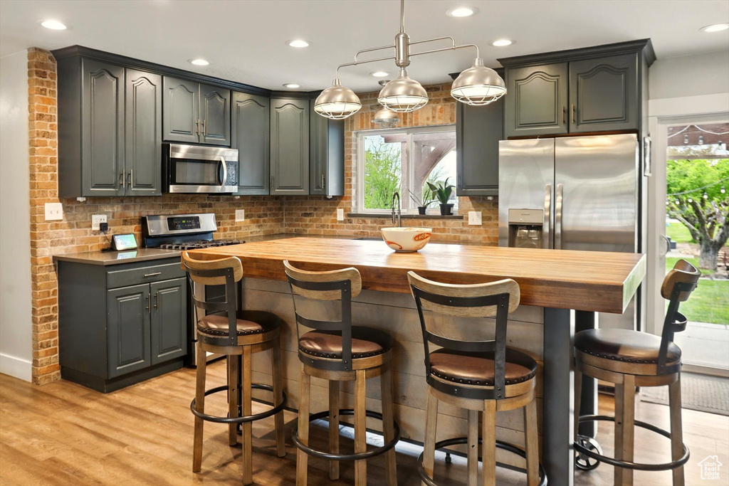 Kitchen featuring wood counters, stainless steel appliances, decorative backsplash, and a healthy amount of sunlight