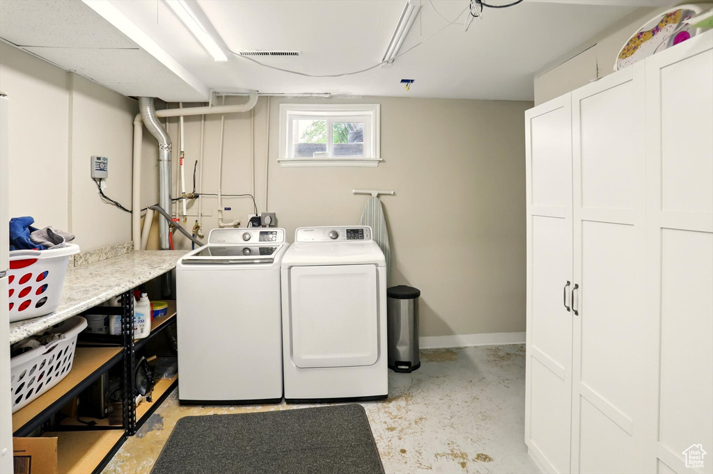 Washroom featuring washing machine and dryer, baseboards, and visible vents