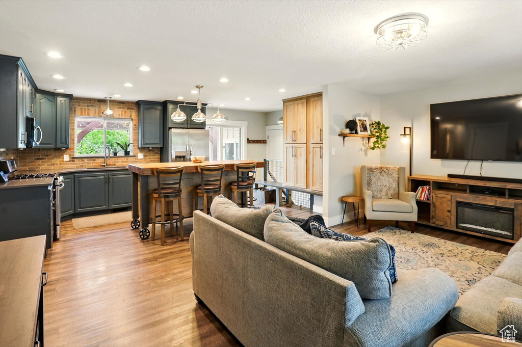 Living room with light wood-style floors, a glass covered fireplace, and recessed lighting
