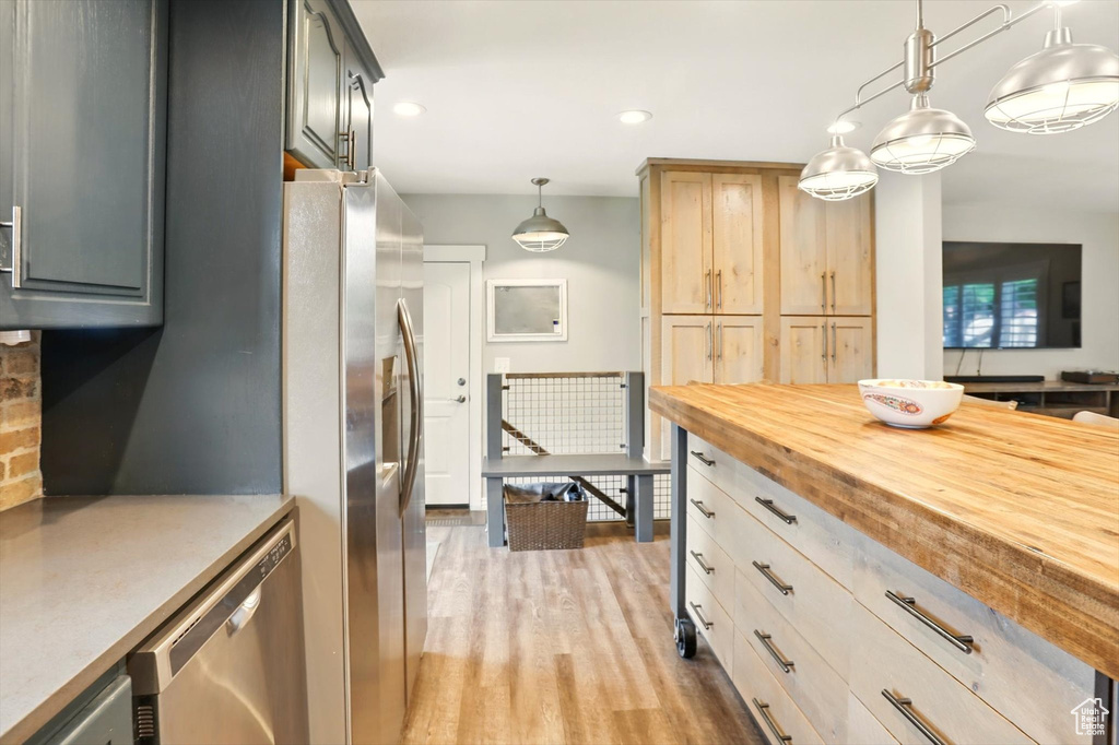 Kitchen featuring butcher block countertops, stainless steel appliances, recessed lighting, pendant lighting, and light wood-style floors