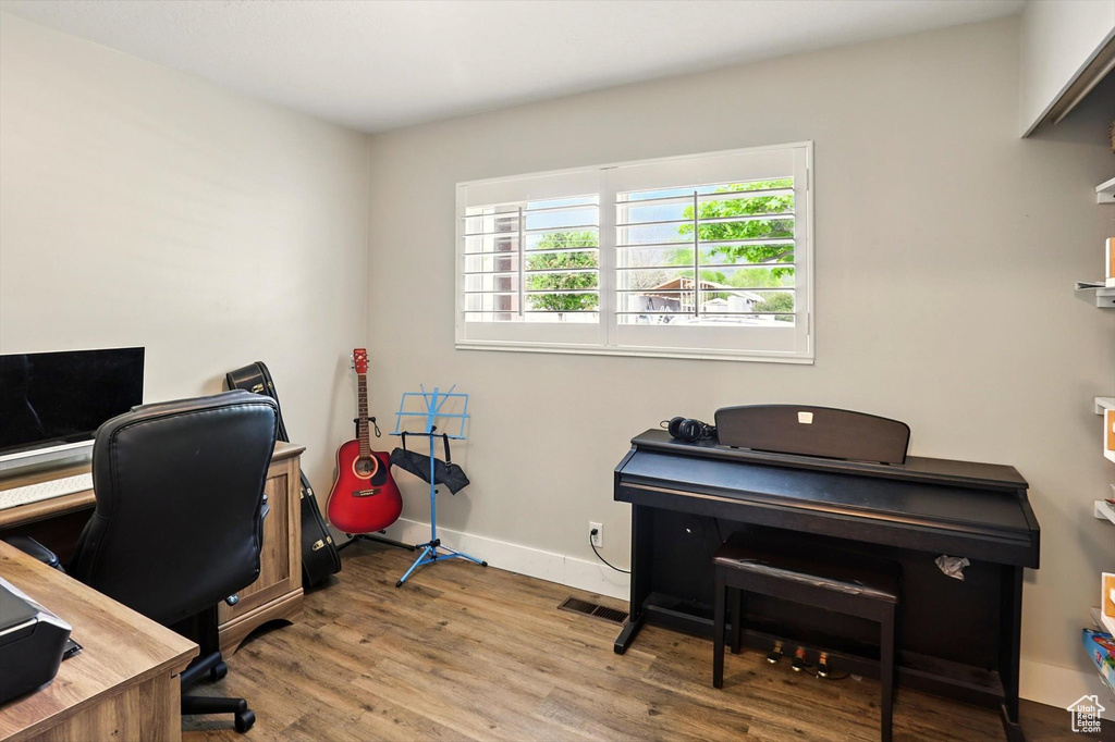 Home office featuring baseboards, visible vents, and wood finished floors